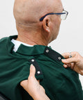 Person adjusting the collar of a green shirt on another person.