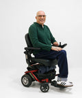 Man sitting in a power wheelchair on a white background