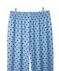 Light blue pants with a dark blue polka dot pattern, featuring an elastic waistband, shown hanging from two clips against a white background.