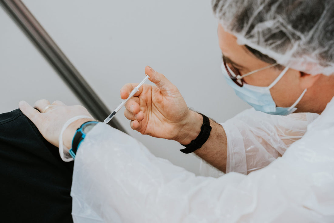 Clinical professional provides vaccination to a patient's arm.