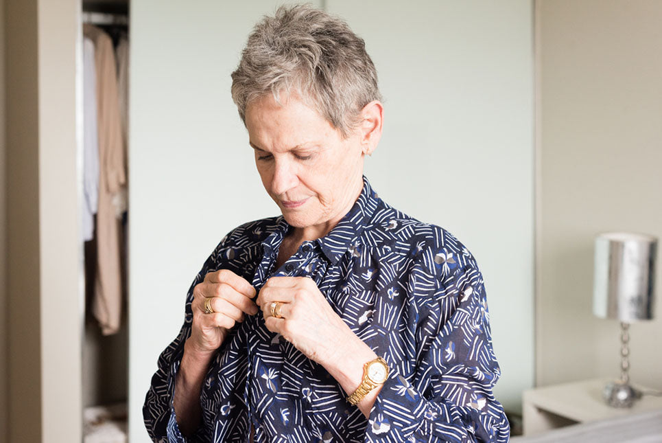 an older woman buttoning her shirt